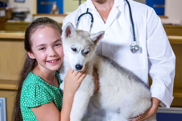 Retrato de menina dando um abraço a um cachorro em braços de veterinários — Fotografia de Stock