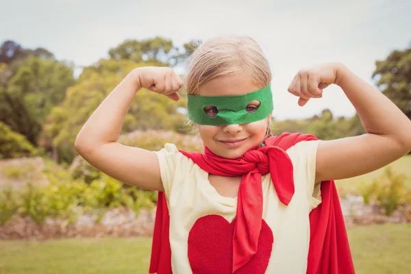 Портрет молодой девушки в платье супергероя показывает ее мышцы — стоковое фото