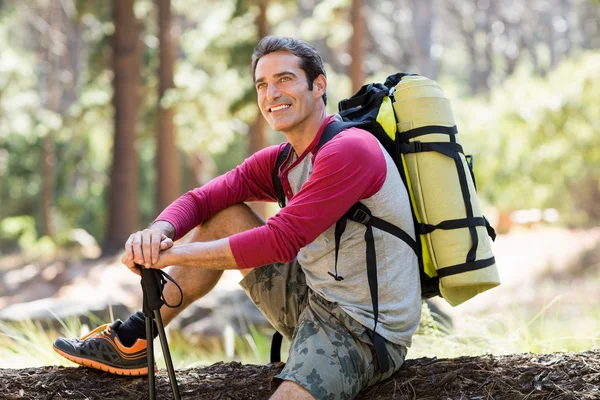 Uomo escursionista sorridente e seduto su un albero — Foto Stock