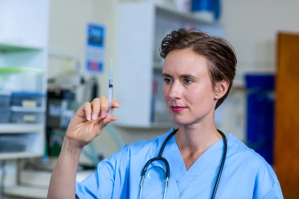 Uma mulher veterinária observando uma seringa — Fotografia de Stock