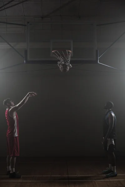 Due giocatori di basket in una palestra con uno che segna un tiro — Foto Stock