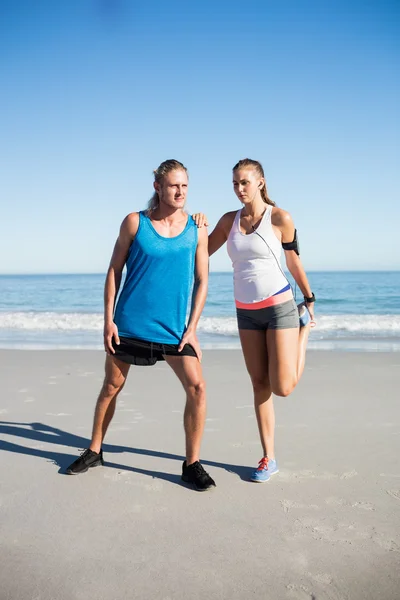 Paar dehnt sich am Strand — Stockfoto