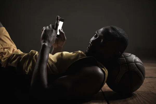 Kosárlabda játékos feküdt, és használ a smartphone portréja — Stock Fotó