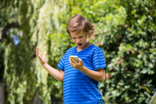 Een kleine jongen is boos op zijn mobiele telefoon — Stockfoto