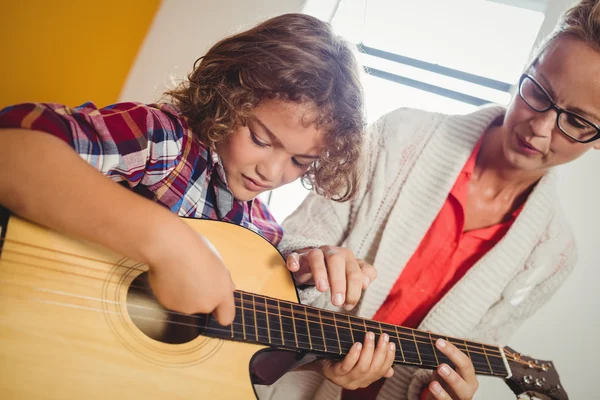 Мальчик учится играть на гитаре — стоковое фото