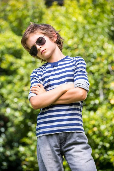 Симпатичный мальчик в солнечных очках, позирует со скрещенными руками — стоковое фото