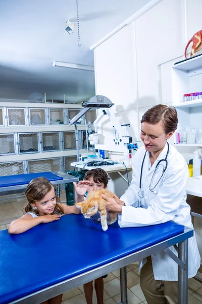 Una mujer veterinaria acariciando a un gatito con niños — Foto de Stock