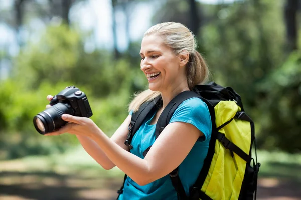 Kobieta uśmiechając się i patrząc jej aparat fotograficzny — Zdjęcie stockowe