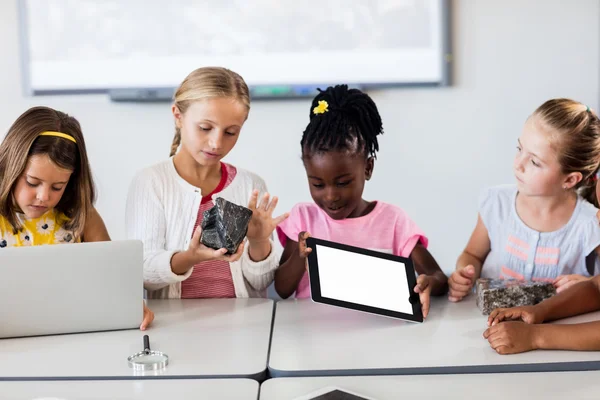 Pupils looking at rock while the others using technology — Stock Photo, Image