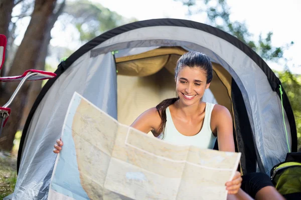 Mujer sonriendo y estudiando un mapa — Foto de Stock