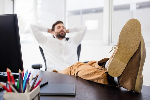 Entspannter Mann mit überkreuztem Bein auf dem Schreibtisch — Stockfoto