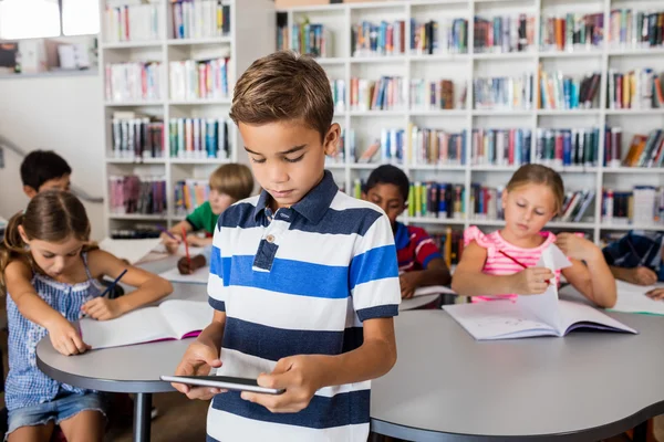 Een leuke jongen staande op zoek op tablet pc — Stockfoto