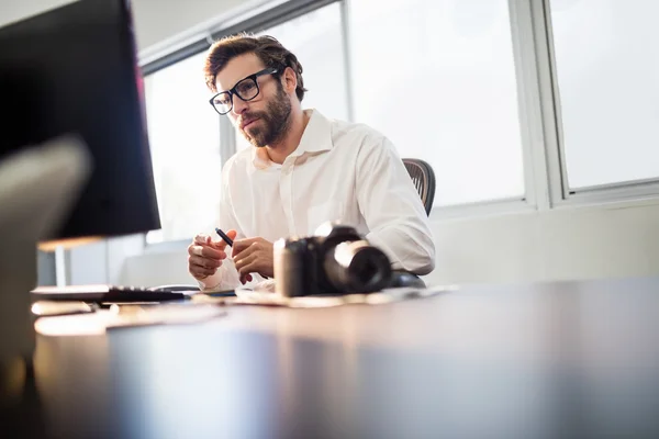 Fotograaf met een bril op zijn computer werkt — Stockfoto