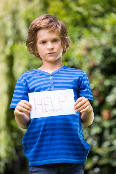 Ernstige jongen houdt van een bericht en tonen aan de camera — Stockfoto