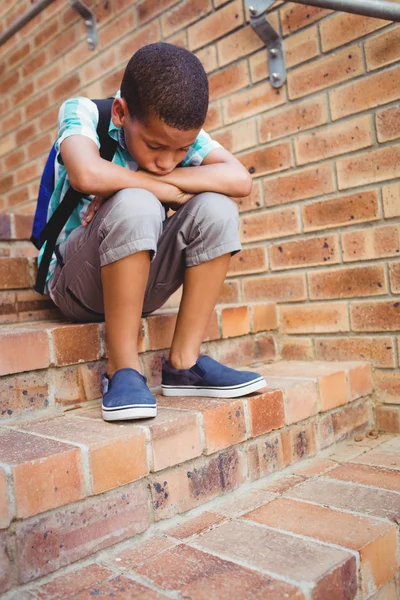 Triest schooljongen met zijn hoofd op zijn knie — Stockfoto