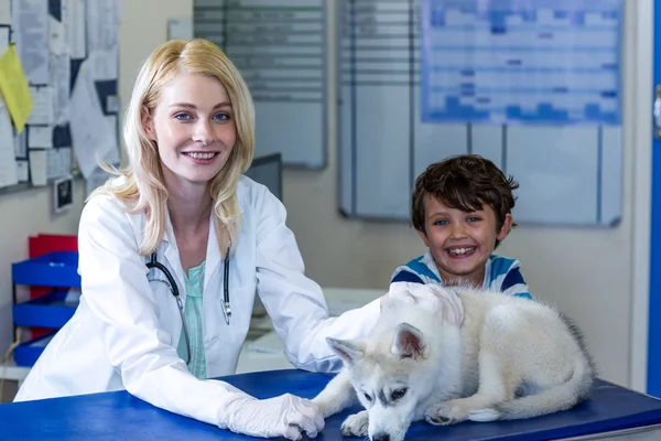 Tierärztin und kleiner Junge lächeln und posieren mit einem süßen Welpen — Stockfoto