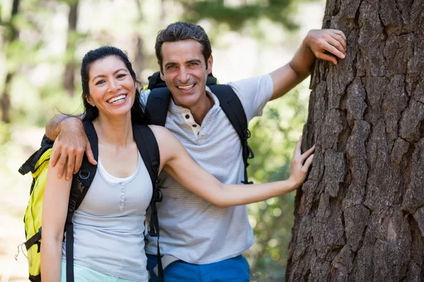 Couple souriant et reposant contre un arbre — Photo