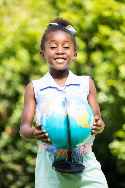 Cute mixed-race girl smiling and holding a globe — Stock Photo, Image