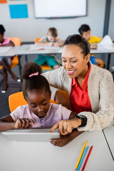 Menina da escola usando tablet na mesa com seu professor — Fotografia de Stock