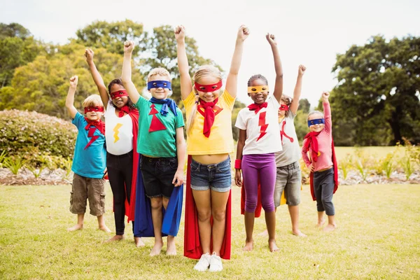 Gruppo di bambini con abito da supereroe in posa con le braccia alzate — Foto Stock