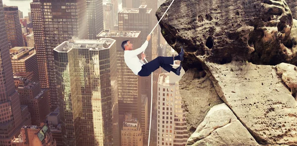 Businessman pulling rope while sitting on cube — Stock Photo, Image