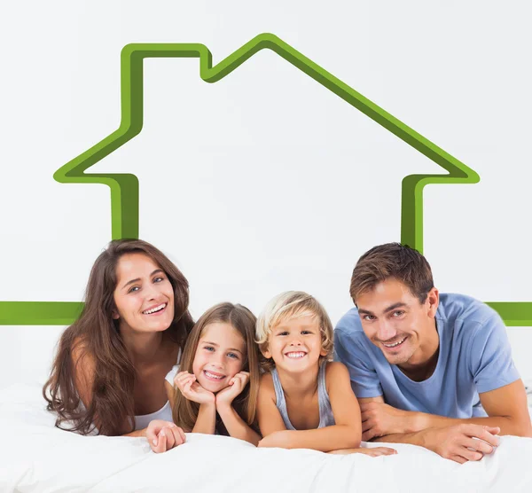 Composite image of happy family lying on a bed — Stock Photo, Image