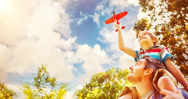 Boy with toy sitting on fathers shoulders — Stock Photo, Image