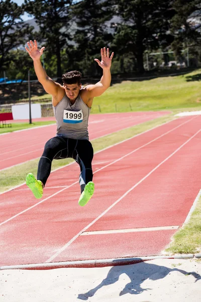 Atleta realizando salto longo — Fotografia de Stock