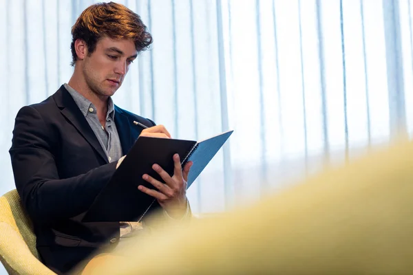 Homme d'affaires prenant des notes sur un livre — Photo