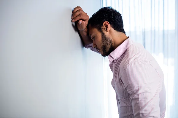 Thoughtful businessman against  wall — Stock Photo, Image