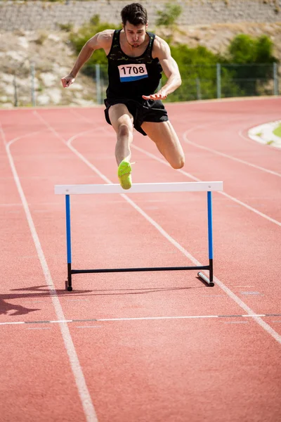 Athlete jumping above the hurdle — Stock Photo, Image