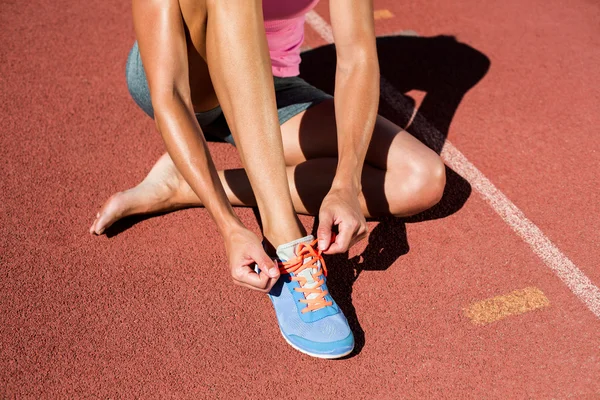 Atleta feminino amarrando seus sapatos de corrida — Fotografia de Stock