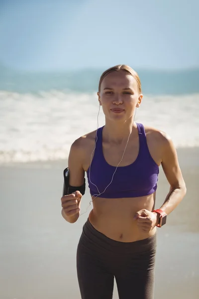 Frau joggt am Strand und hört Musik — Stockfoto