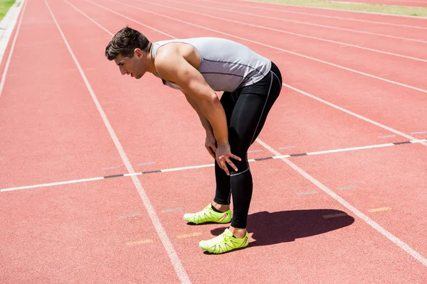 Atleta cansado em pé na pista de corrida — Fotografia de Stock