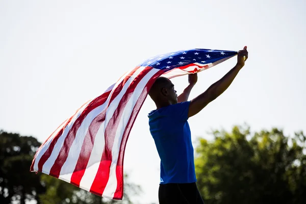 Idrottsman innehar en amerikansk flagga — Stockfoto