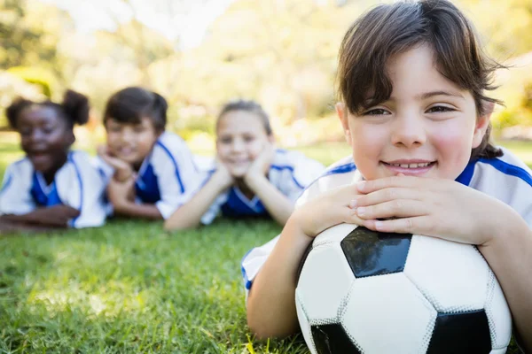 Flicka liggande på golvet med fotbollslag — Stockfoto