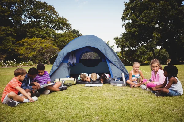 Des enfants souriants couchés et lisant dans la tente ensemble — Photo