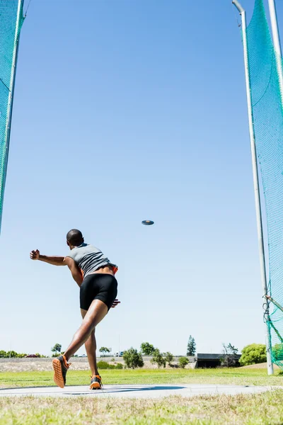 Athlete throwing discus in stadium — Stock Photo, Image