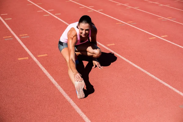 Kvinnelig friidrettsutøver som strekker seg – stockfoto