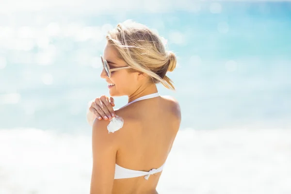 Mujer aplicando crema solar en el hombro —  Fotos de Stock