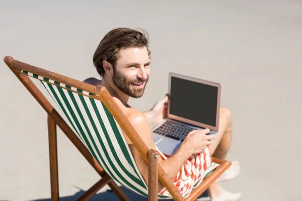 Человек, сидящий на кресле на пляже — стоковое фото