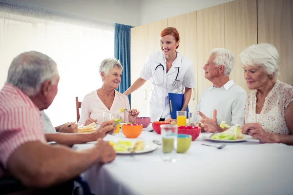 Pensionärer på lunch med sjuksköterska — Stockfoto