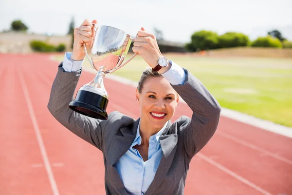 Happy businesswoman holding up trophy — Stock Photo, Image