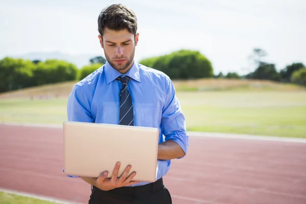 Empresário usando laptop na pista de corrida — Fotografia de Stock