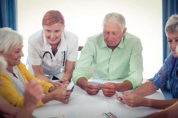 Gepensioneerden speelkaarten met verpleegkundige — Stockfoto