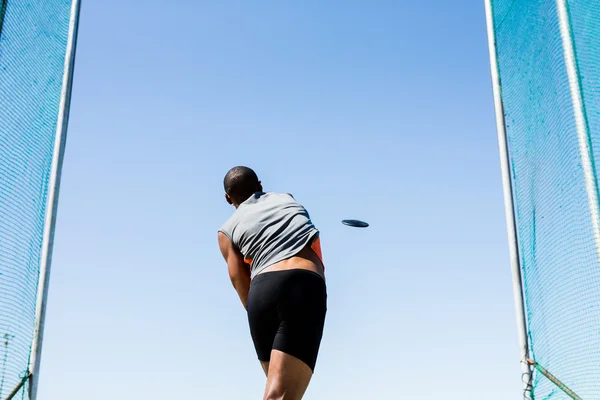 Athlete throwing discus in stadium — Stock Photo, Image