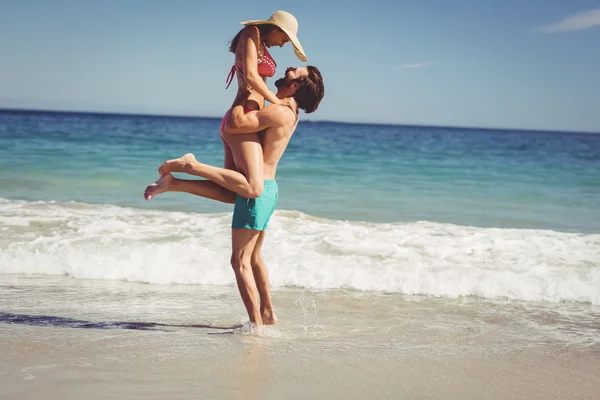 Чоловік піднімає жінку на пляжі — стокове фото
