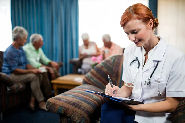 Krankenschwester schreibt auf Klemmbrett — Stockfoto