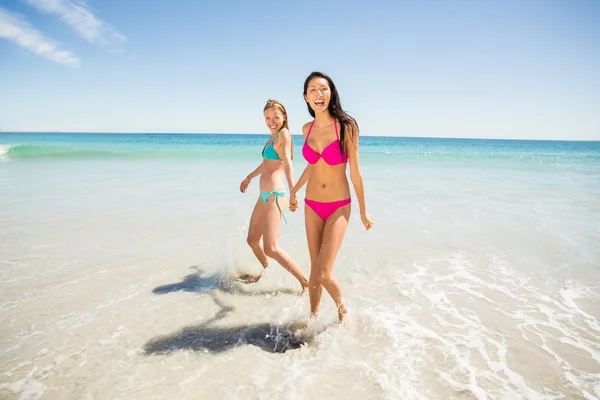 Female friends holding hands on beach — Stock Photo, Image