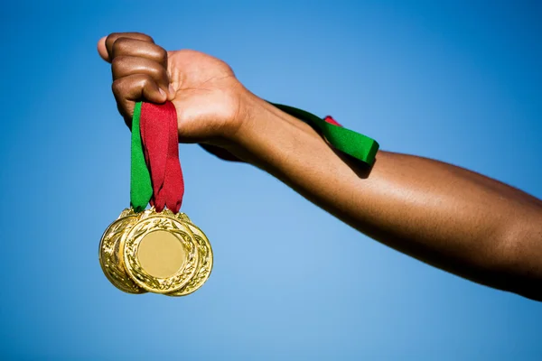 Athlete hand showing gold medals — Stock Photo, Image